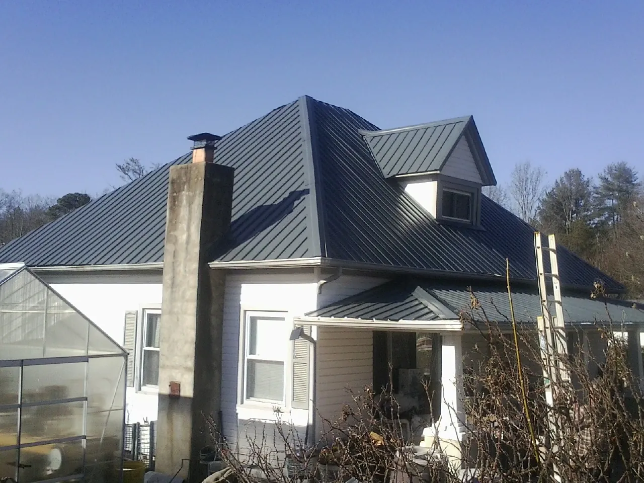 Dark blue standing seam metal roof on a white farmhouse with dormer — Slate & Tile Roof Repair by Roofing Brothers in Norwich